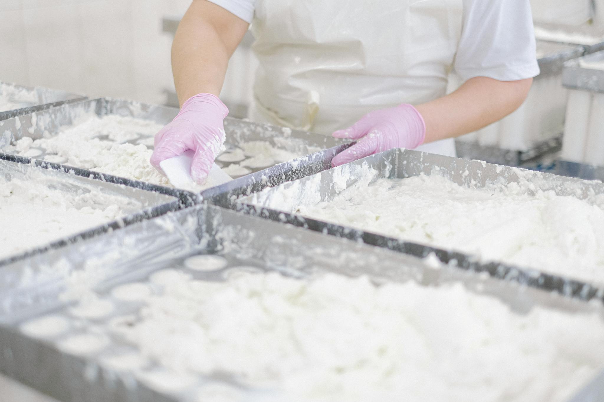 A person using pink gloves to prepare dough in a commercial baking facility.
